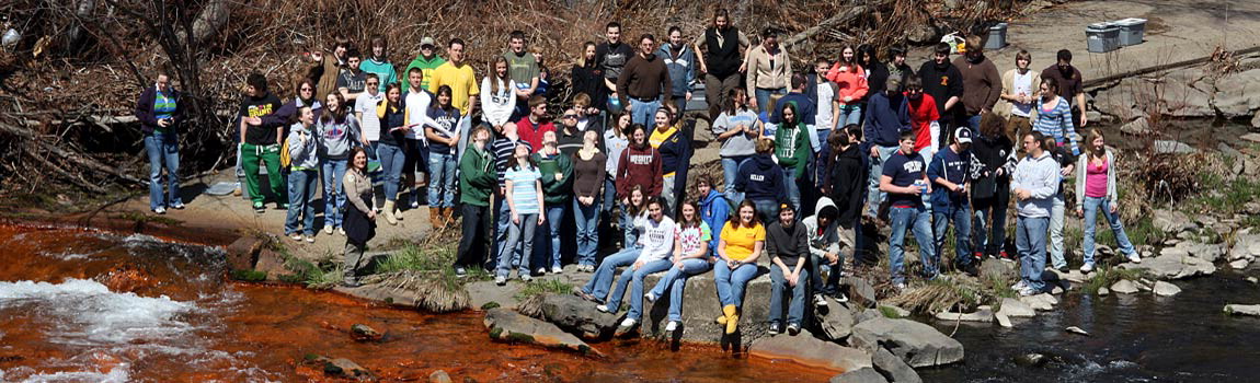 Students and state park staff stand at the confluence of two creeks, one clean, one polluted.